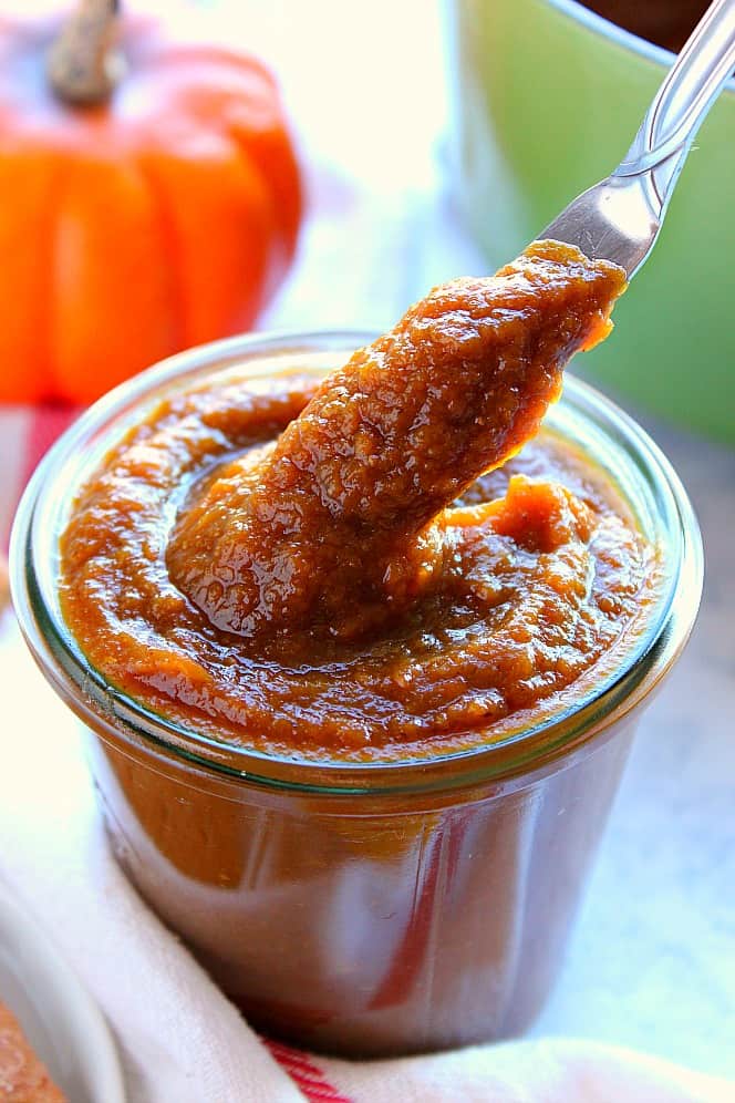 Easy Pumpkin Butter Recipe - quick and delicious homemade pumpkin butter with spices, apple cider and orange! Make in two steps and enjoy all season long! Close up shot of pumpkin butter on butter knife taken from glass jar.