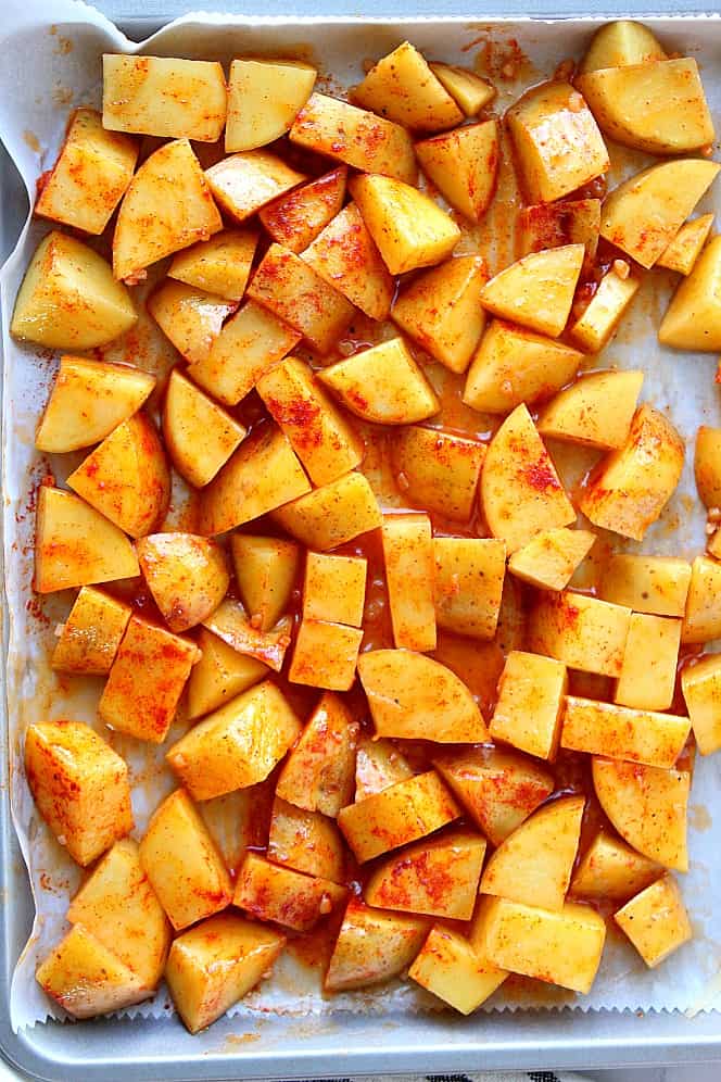 Overhead shot of potatoes coated with paprika butter on a baking sheet. 