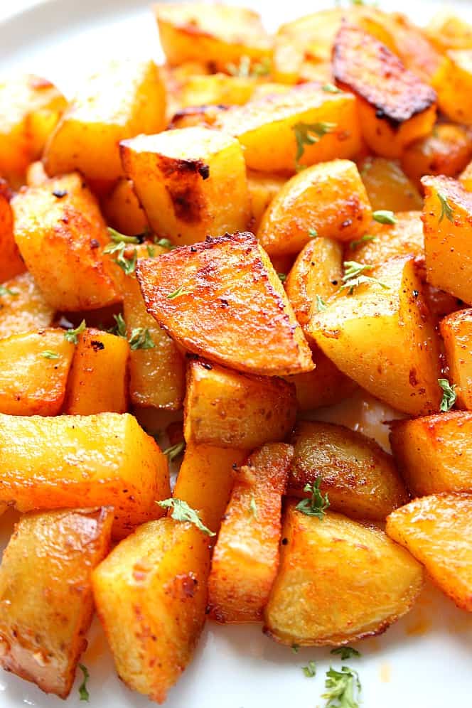 Easy Oven Roasted Potatoes Recipe - crispy on the outside and soft on the inside, these roasted potatoes are the easiest side dish ever! Close up photo of perfectly roasted potatoes on white plate.