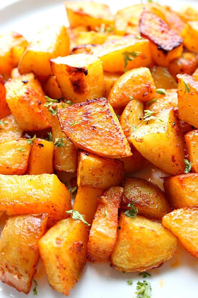 Close up photo of perfectly roasted potatoes on white plate. 