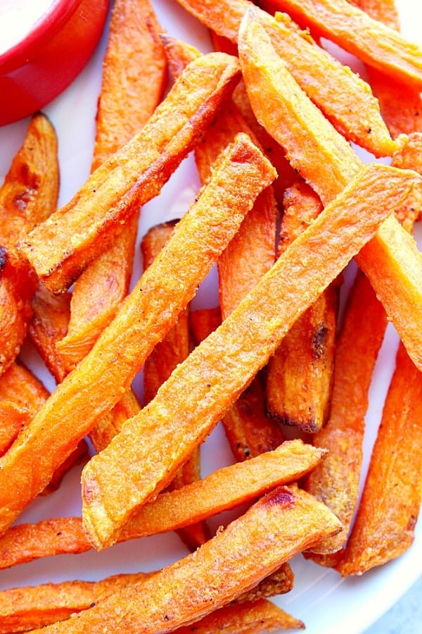 Overhead close up shot of sweet potato fries on white plate.