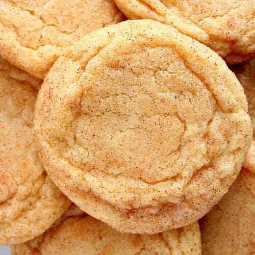 Square image of snickerdoodle cookies stacked on a plate.