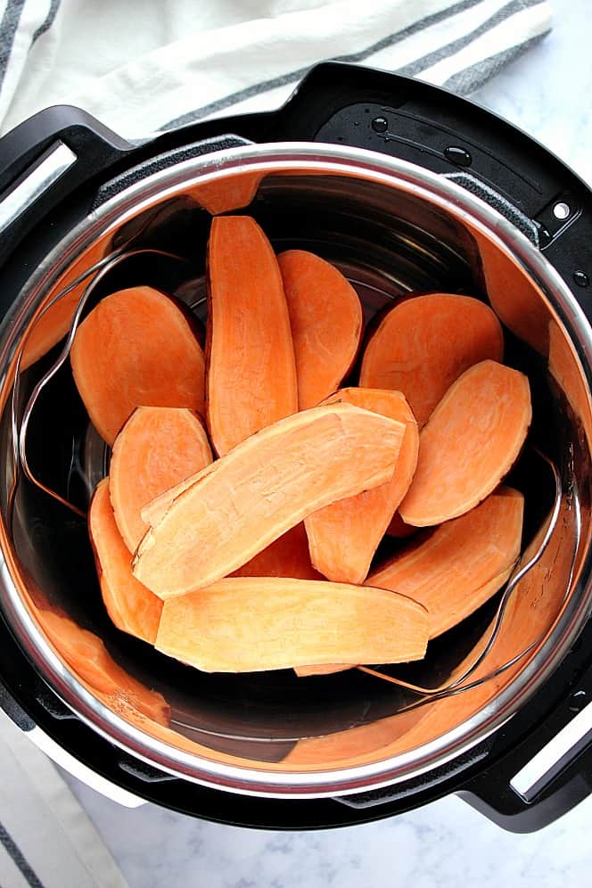 Overhead shot of sweet potatoes sliced in half, stacked on trivet in Instant Pot.