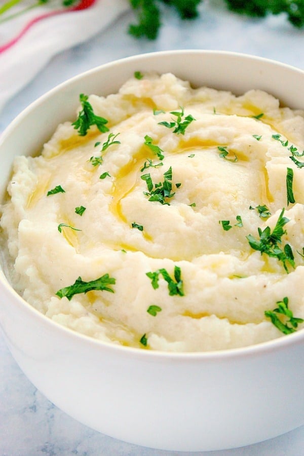 Mashed Cauliflower with chopped parsley in white bowl.