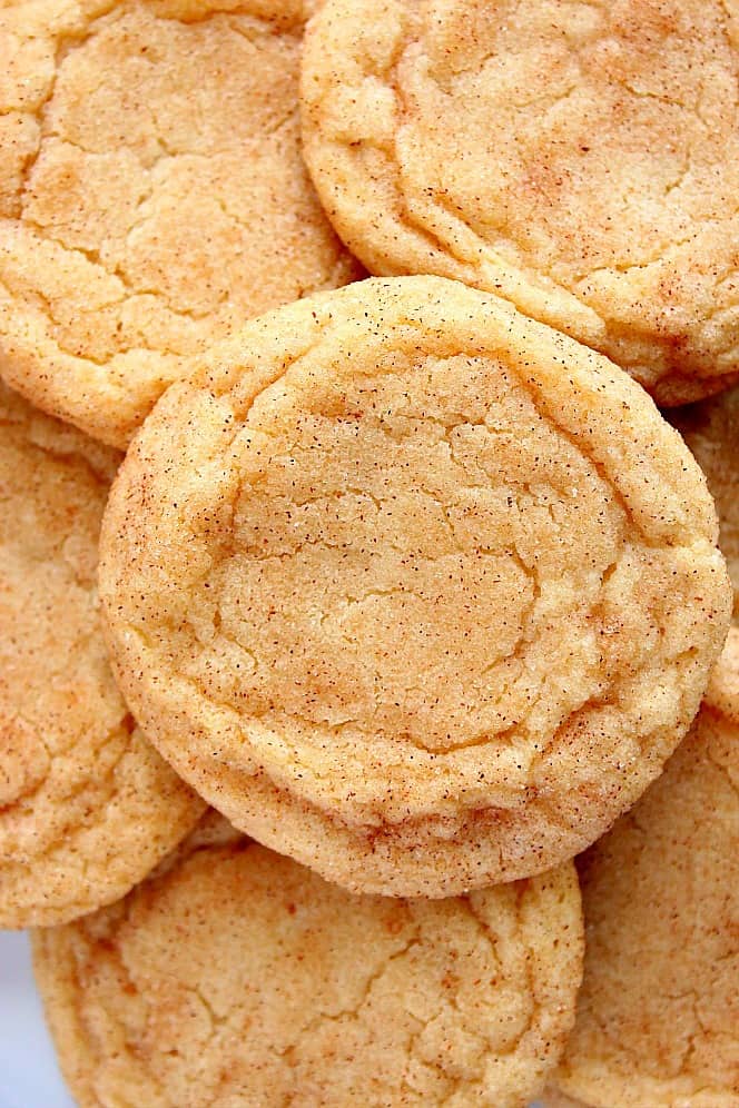 Overhead close up shot of snickerdoodle cookies stacked on each other on plate. 