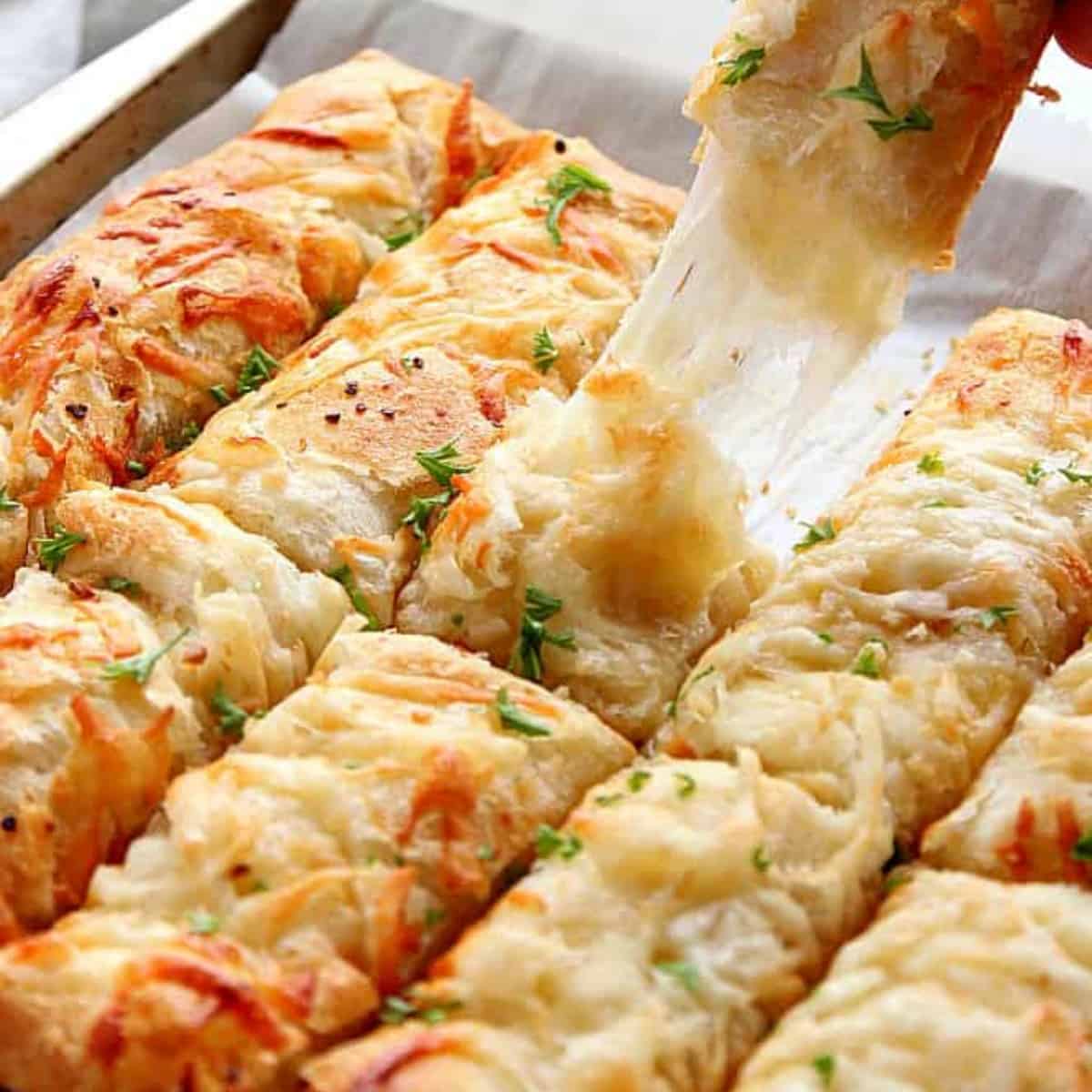 Cheesy breadsticks on baking sheet.