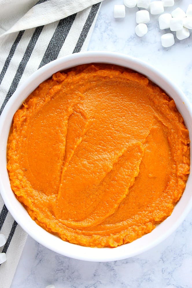 Overhead shot of mashed sweet potato mixture spread evenly in round baking dish.