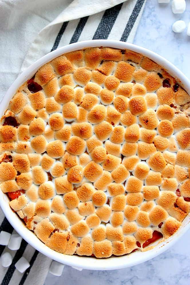 Overhead shot of sweet potato casserole with toasted marshmallow topping, in white round casserole dish.