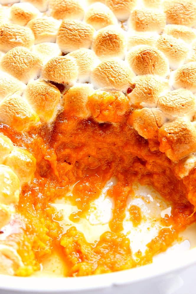 Close up shot of inside cut of sweet potato casserole with marshmallow topping.