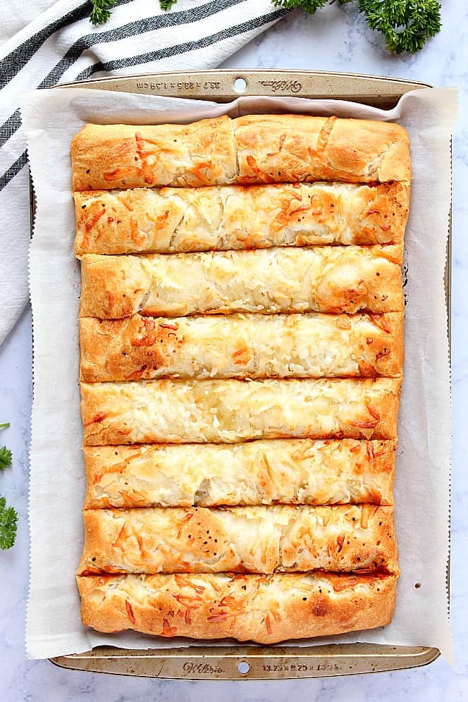 Overhead shot of baked golden breadsticks in baking pan. 