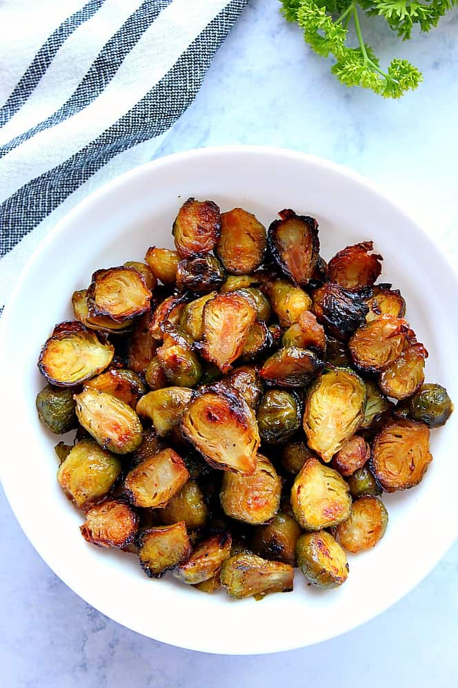 Overhead shot of roasted Brussels sprouts in white serving bowl. 