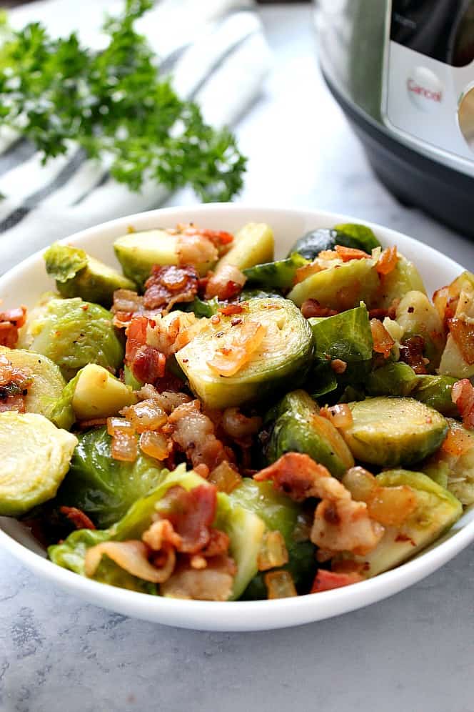 Side shot of Brussels sprouts with bacon, in serving bowl, with Instant Pot in the background.