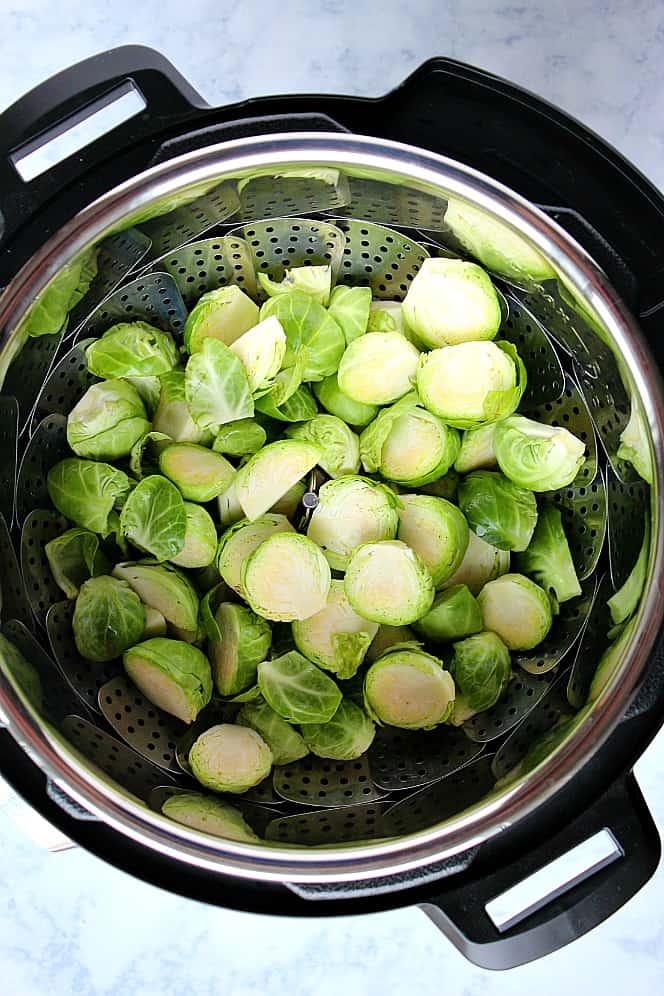 Overhead shot of fresh Brussels sprouts, cut in half, in steamer basket inside Instant Pot.