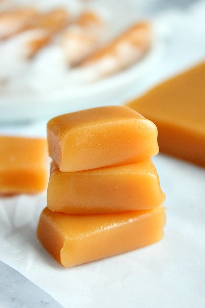 Easy Microwave Caramels recipe - buttery and soft caramels made in just 7 minutes in the microwave. This is the easiest way to make this homemade candy! #caramel #microwavecandy #candy #Christmascandy Side shot of three pieces of homemade microwave caramels stacked on each other.