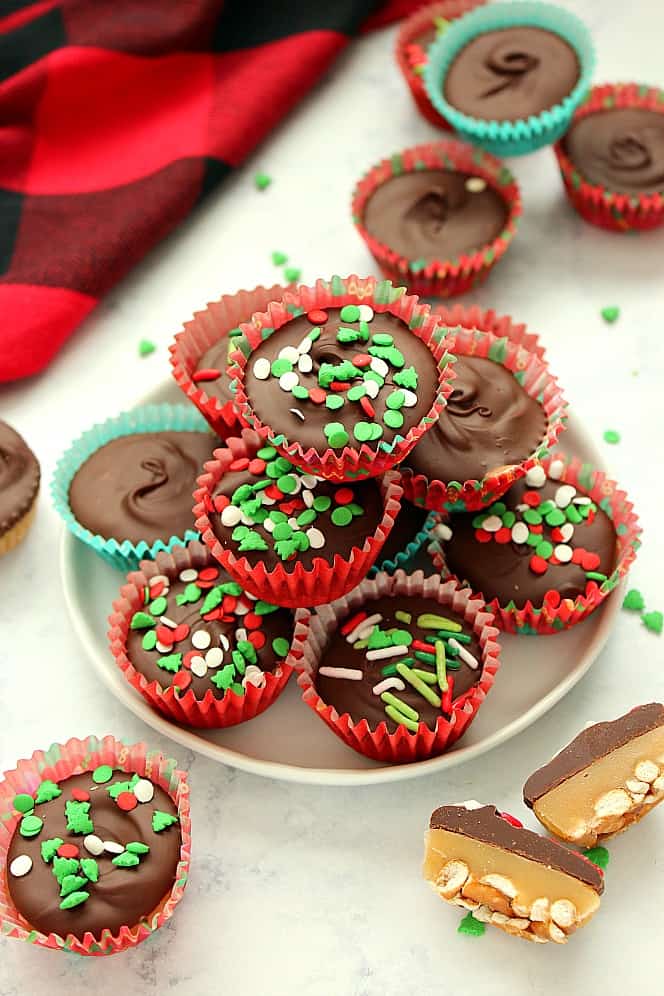 Side shot of chocolate cups with Christmas sprinkles stacked up on white plate.