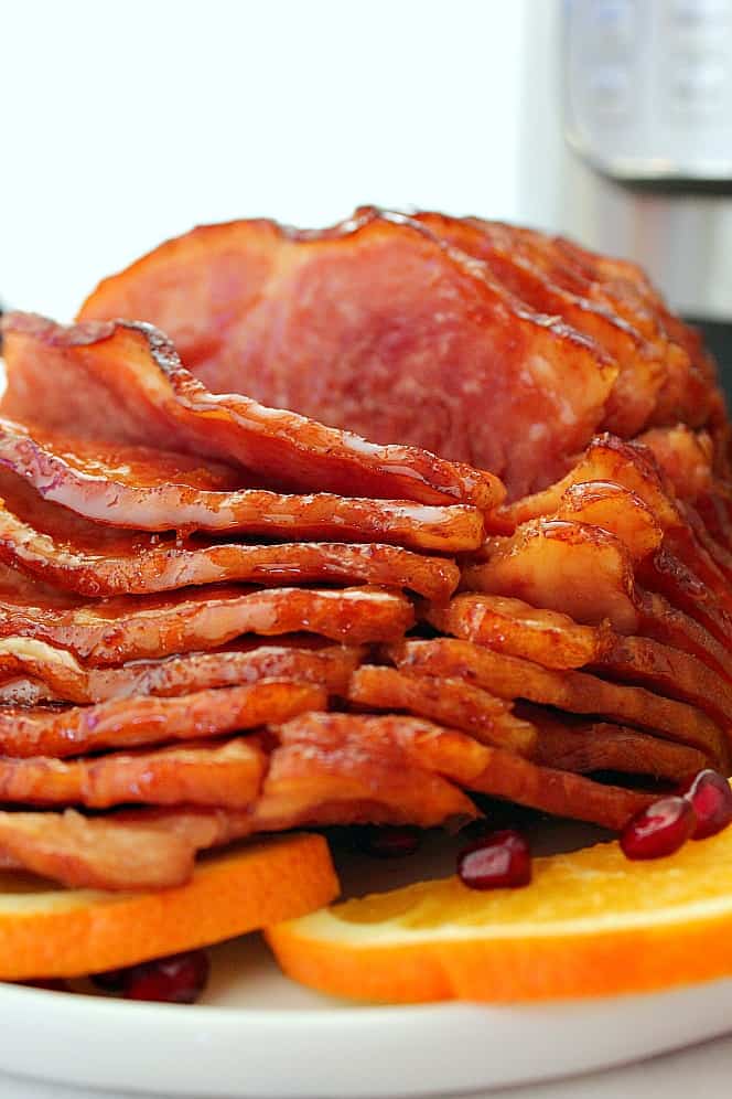 Close up shot of glazed sliced ham on white serving platter. 