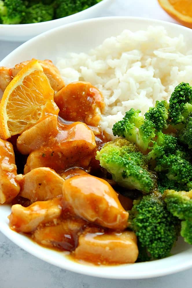 Skinny Orange Chicken Recipe - quick and easy Asian dish with chicken in citrus sauce. Perfect served with rice and steamed vegetables. #chicken #healthy #orange Close up shot of Skinny Orange Chicken with broccoli and rice in a bowl.
