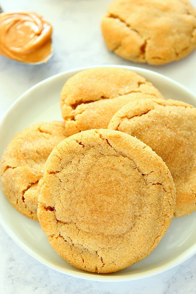 Side shot of four peanut butter cookies on white plate. 