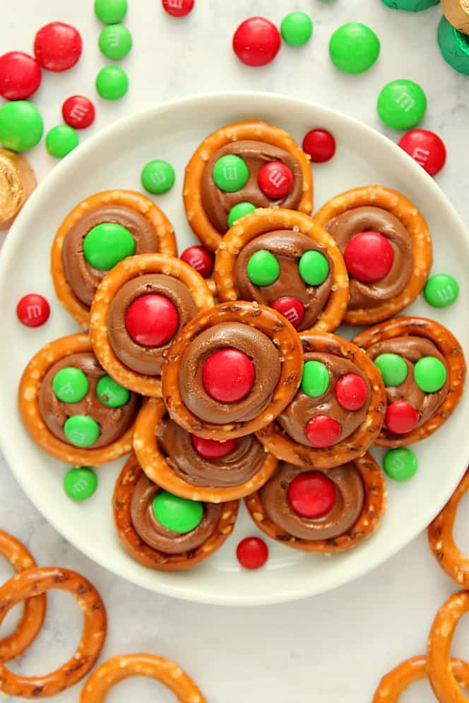 Overhead shot or pretzels with Rolo candy and red and green M&M's on white plate. 