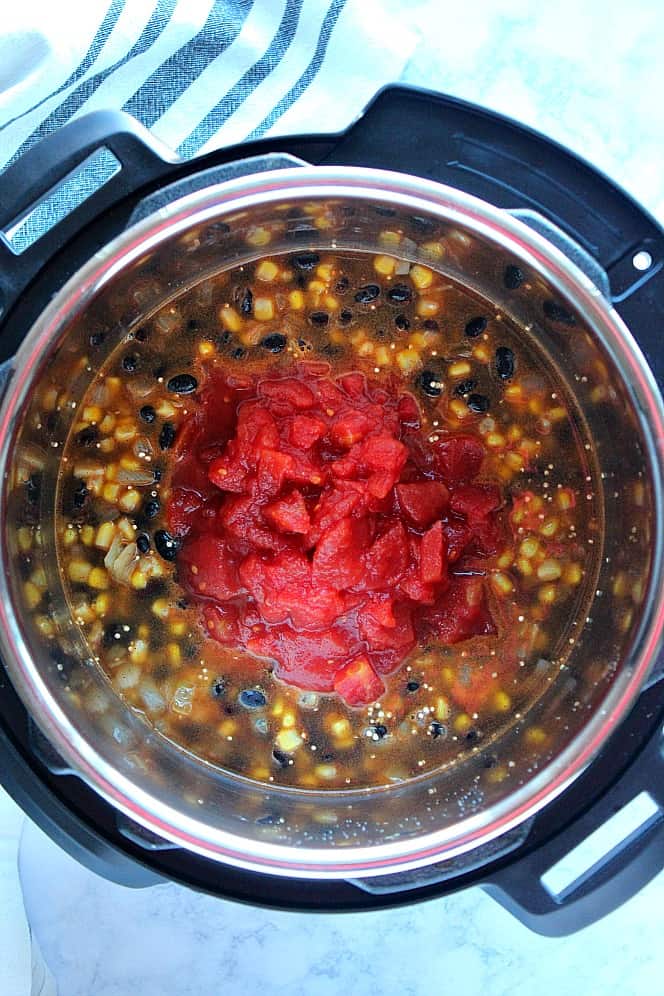 Overhead shot of quinoa, black beans and corn with diced tomatoes on top, in the Instant Pot.