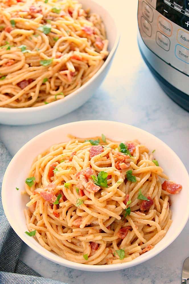 Side shot of two bowls with pasta carbonara and Instant Pot next to them.