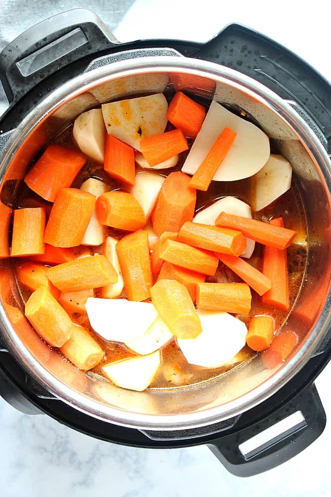 Overhead shot of carrots and potatoes on top of pot roast in the Instant Pot. 