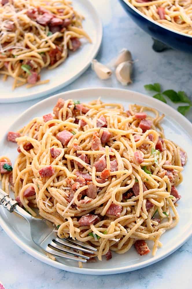 Side shot of spaghetti carbonara on white plate.