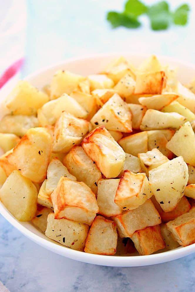 Side shot of roasted potato chunks in white bowl. 