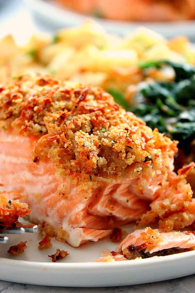 Garlic Parmesan Crusted Salmon Recipe - quick and easy salmon with crunchy garlic butter Parmesan crust can be baked in your oven or air fryer. This salmon is flavorful, flaky, buttery and delicious! Parmesan Crusted Salmon on plate with potatoes and spinach.