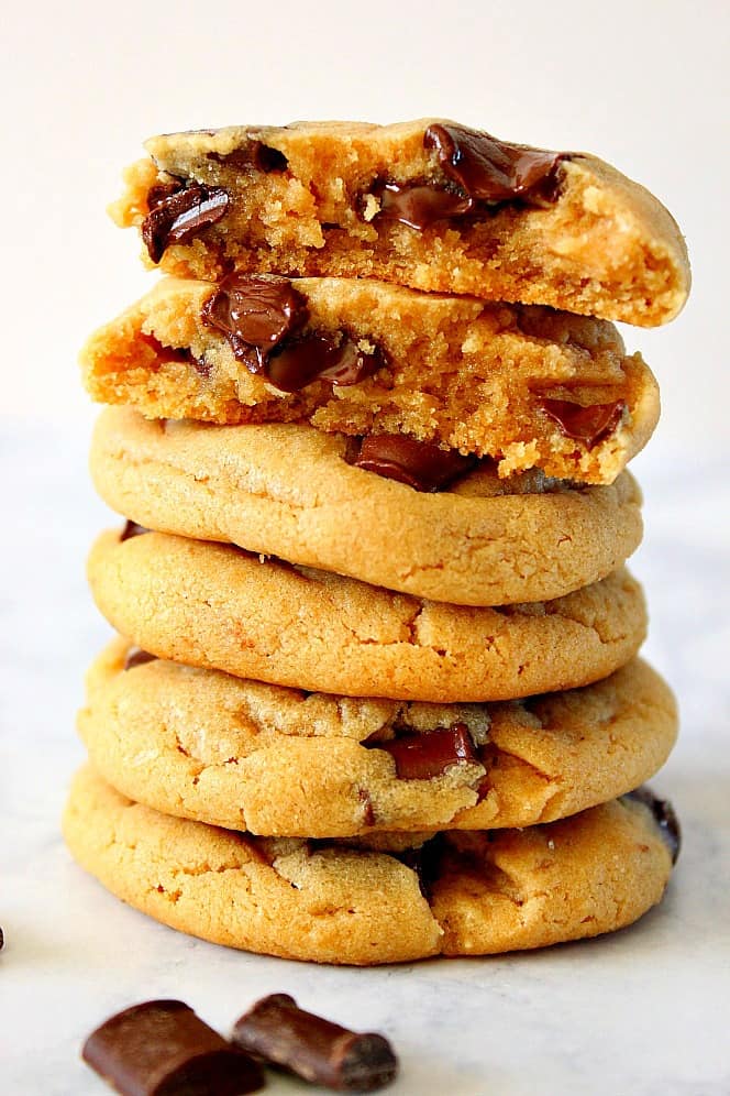 Side shot of 5 peanut butter chocolate chunk cookies, stacked up on each other, the top one broken in half.