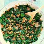 Sauteed spinach with onions in white skillet.