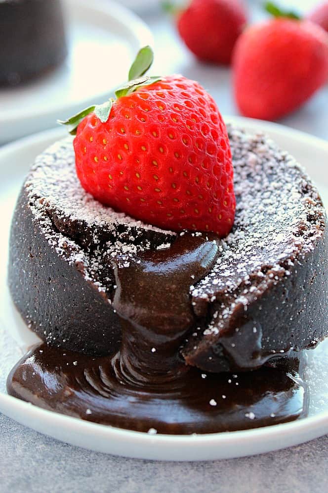 Close up shot of lava cake with gooey center, topped with strawberry.