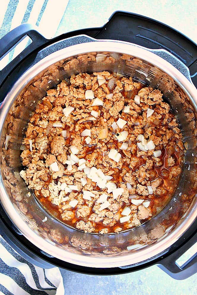 Overhead shot of ground chicken with chopped water chestnuts in the Instant Pot. 