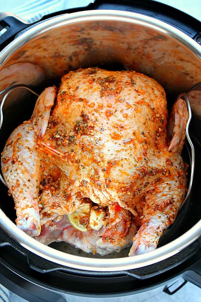 Overhead shot of whole raw chicken, rubbed with seasoning, in the Instant Pot.