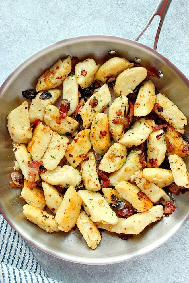 Overhead shot of Polish potato dumplings in stainless steel skillet.