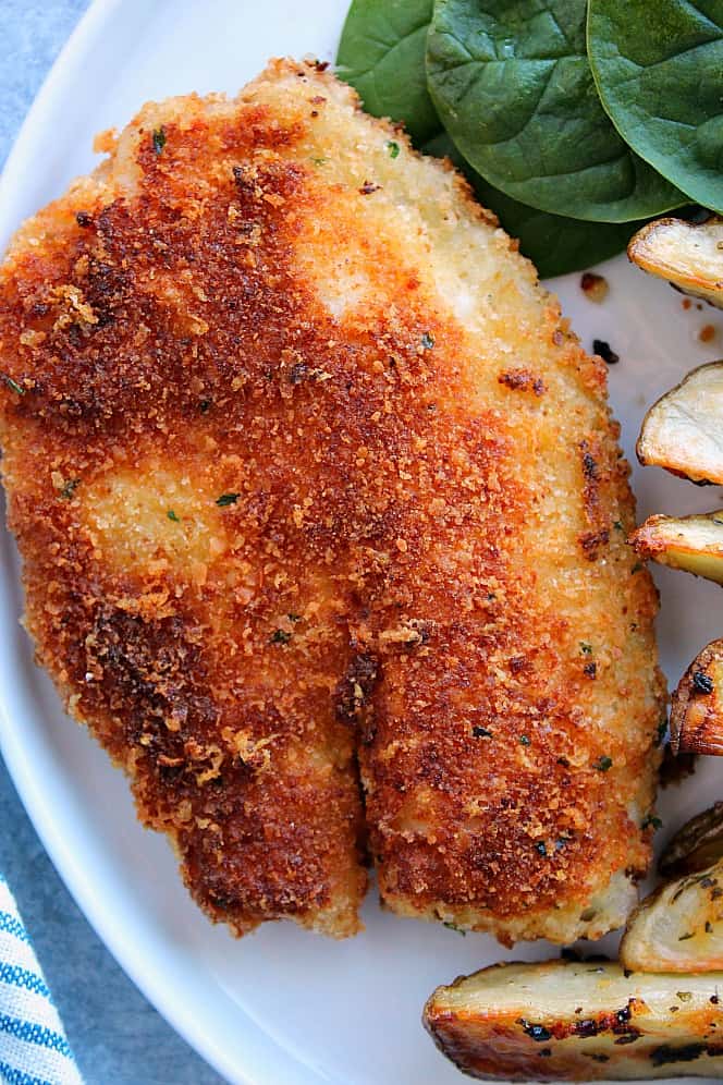 Overhead shot of crispy fried tilapia with Parmesan breading, on white plate.