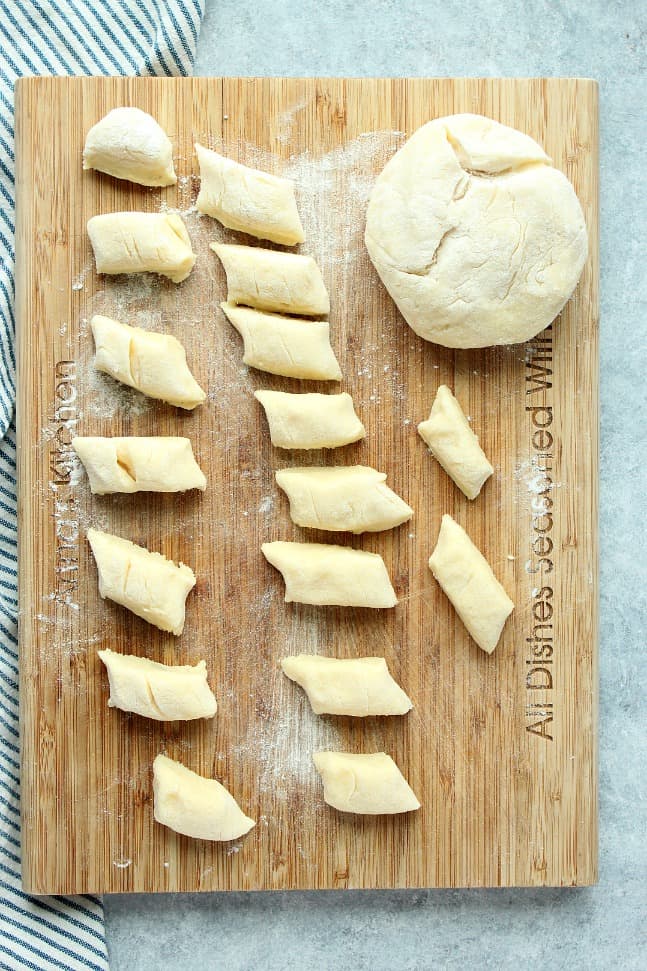 Overhead shot of cut Polish potato dumplings on wooden cutting board.