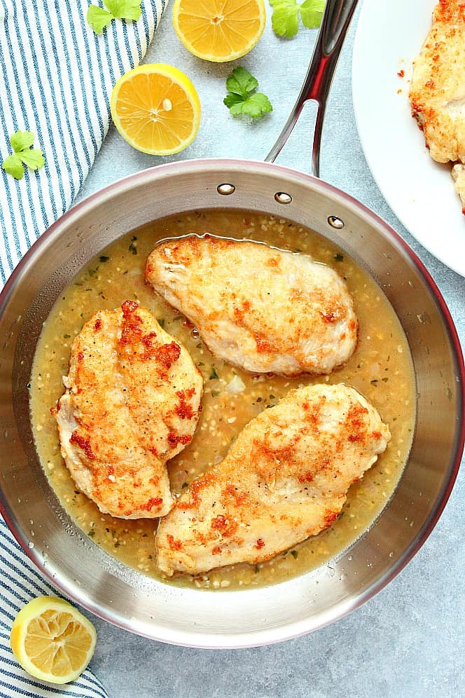 Overhead shot of three chicken breasts in stainless steel skillet.