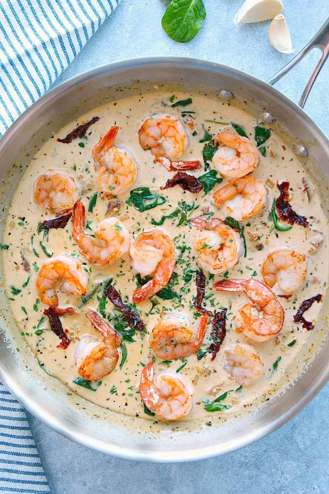 15-Minute Creamy Tuscan Shrimp - fast and easy shrimp in a creamy sauce made with sun-dried tomatoes, garlic and spinach. This dinner is perfect for busy weeknights! Overhead shot of Tuscan Shrimp in stainless steel pan.