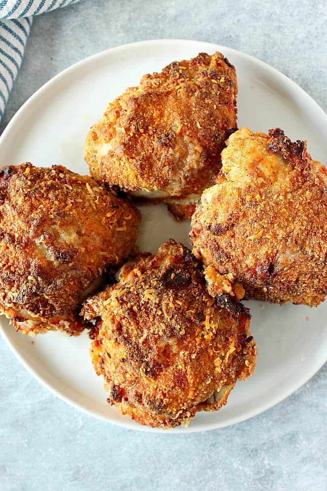 Four air fried chicken thighs on white plate.