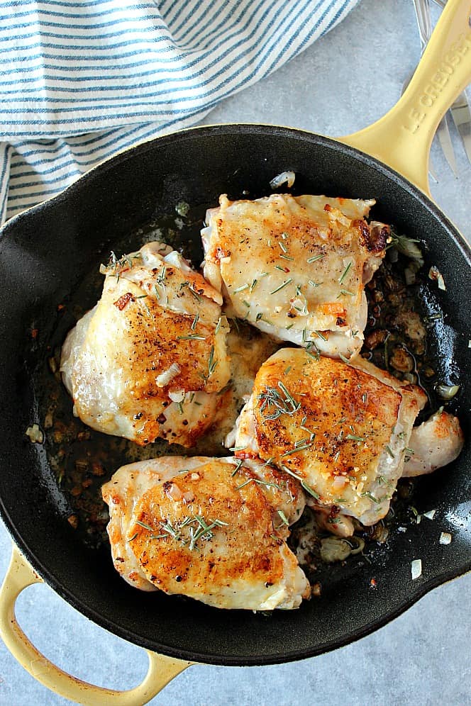 Overhead shot of 4 chicken thighs in cast iron skillet.