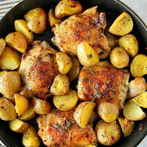 Chicken thighs and potatoes in skillet.