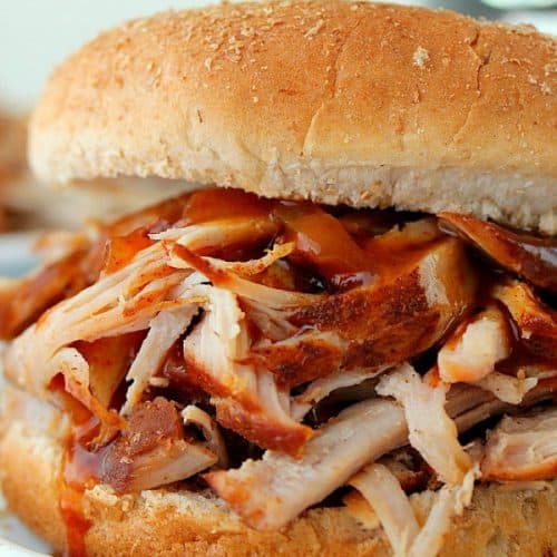 Instant Pot Pulled Pork in a bun on white plate.