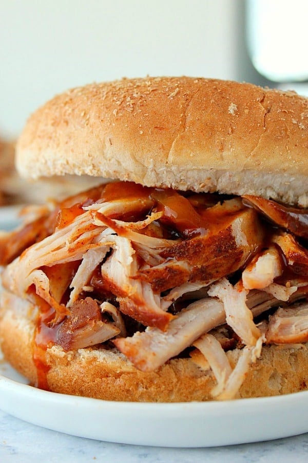 Instant Pot Pulled Pork in a bun on white plate.