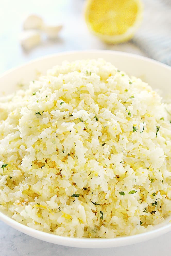 Close up shot of lemon garlic cauliflower rice in white bowl.