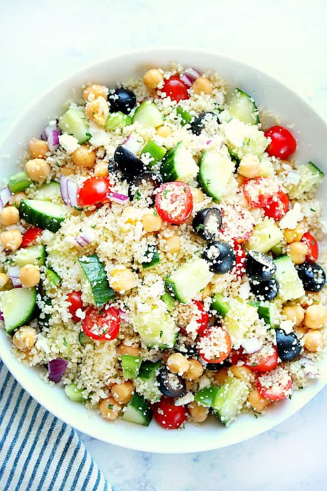 This Mediterranean Couscous Salad is a healthy and light option for lunch or dinner. Overhead shot of Mediterranean Couscous Salad in white bowl.