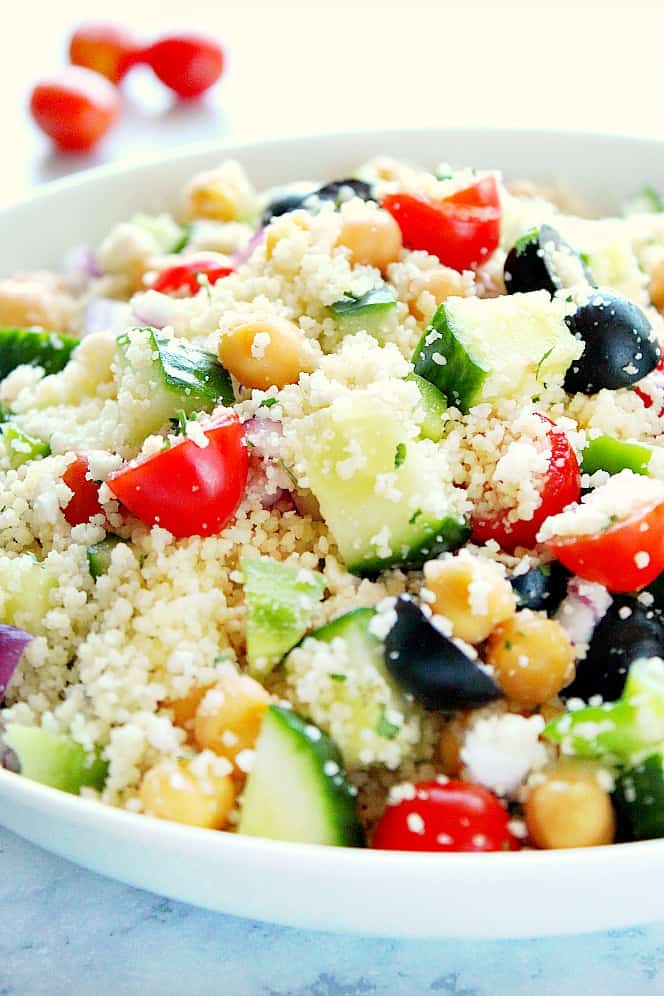 Close up shot of couscous salad with cucumber, tomatoes, olives and chickpeas.