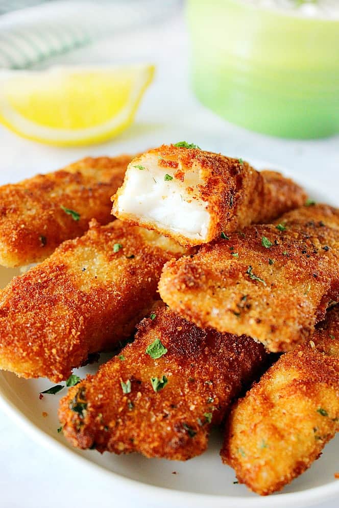 Close up shot of golden brown fish sticks on plate.