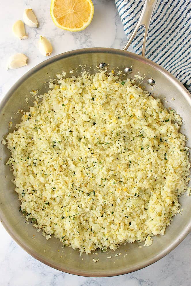 Overhead shot of lemon garlic cauliflower rice in stainless steel pan.
