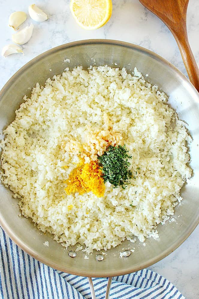 Overhead shot of cauliflower rice, lemon zest, garlic and parsley in pan.